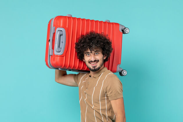 视图带着大箱子的男人在度假 脸上挂着蓝色的微笑成人行李手套