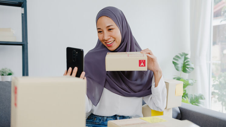 购买年轻的女商人博客使用手机摄像头录制vlog视频直播审查产品在家办公电子商务订单阿拉伯语
