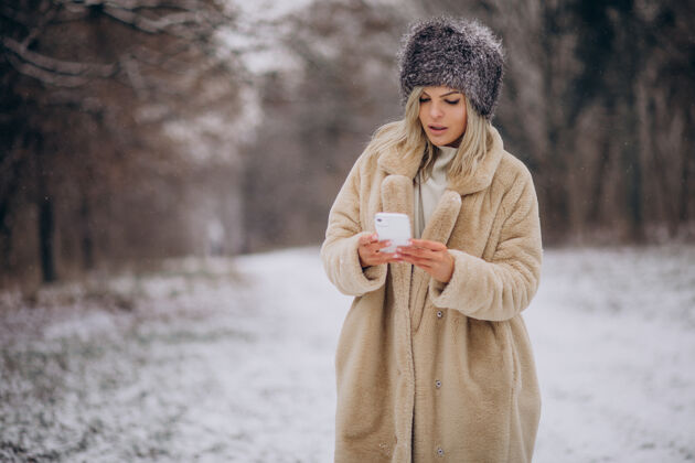 毛衣穿着冬衣的女人走在满是雪的公园里打电话女孩女性休闲
