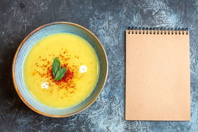 汤上图是螺旋笔记本和蓝色桌子上盛着美味汤的蓝色锅美味美味的汤晚餐