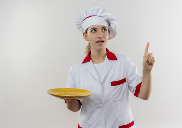 空年轻漂亮的厨师穿着厨师制服 拿着空盘子 孤零零地站在白色的墙上 望着上面 给人留下了深刻的印象厨师制服漂亮