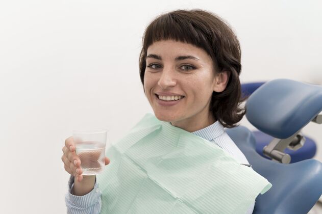 职业女病人在牙科手术前在牙科诊所喝水工作牙医水