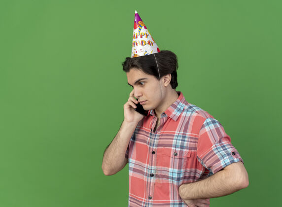 穿一个戴着生日帽的白人帅哥站在一边打电话绿色空间生日