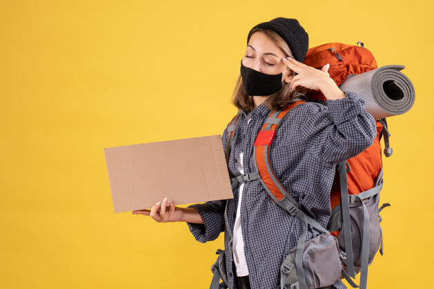 黑人带着黑色面具和背包的旅行女孩闭上眼睛拿着纸板面具纸板眼睛