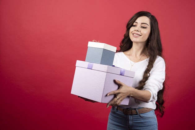 姿势长发女士站在红色背景上 拿着礼物盒高质量的照片人礼物站立