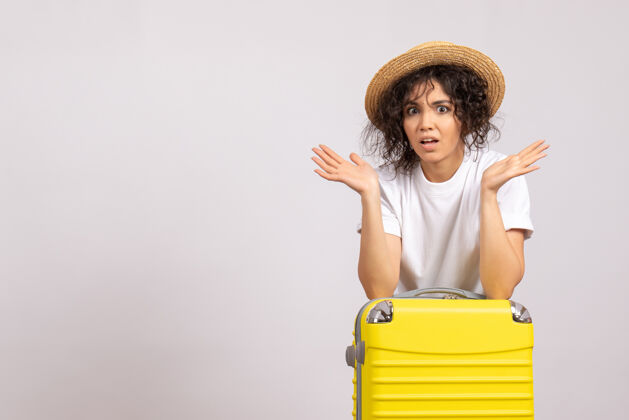 旅行正面图年轻女性带着黄色袋子准备乘坐白色背景色的航班旅行度假飞机阳光旅游者休闲微笑飞行