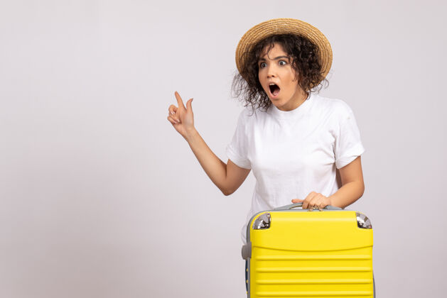 人正面图年轻女性带着黄色的包准备旅行震惊于白色背景上的航班休息航程旅游度假彩色飞机晒太阳年轻女性家庭主妇美丽