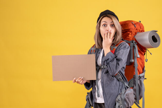 女商人一个背着背包拿着纸板的出其不意的女旅行者背包时尚模型