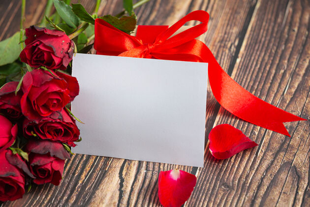 礼物玫瑰红色的花朵和包裹在深色木头背景上花束盒子玫瑰