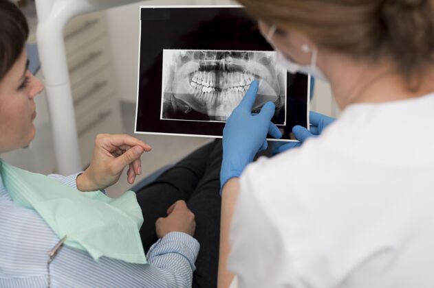 工人女病人和牙医一起看牙齿的X光片病人牙医牙科工作