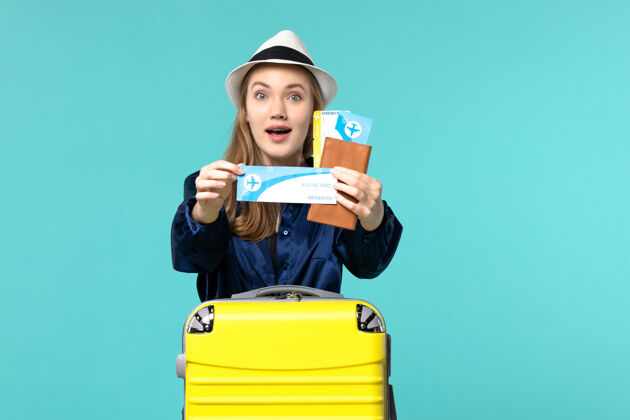 工作正面图年轻女子拿着机票 准备在蓝色背景上旅行 飞机航行 海上度假旅行举行年轻女子准备