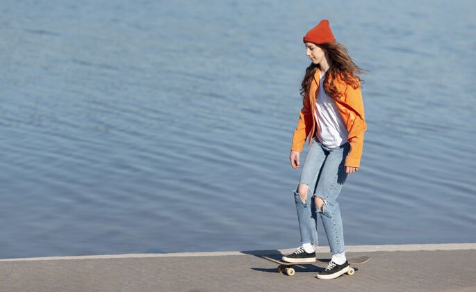 街头在湖边滑冰的年轻女孩生活方式滑板全速
