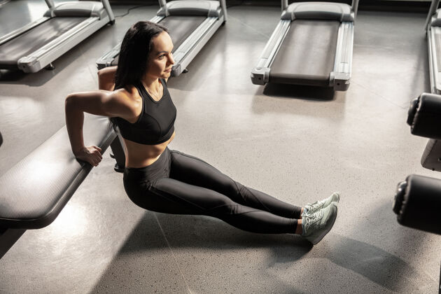 形状年轻肌肉发达的女人在健身房练习设备室内重量重