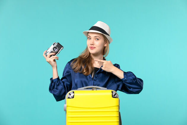 肖像前视图年轻女子手持相机 准备在蓝色背景上旅行度假旅行飞机海上旅程相机人
