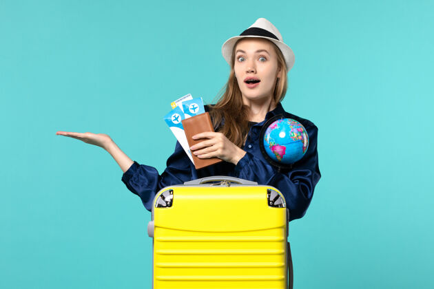票正面图年轻女子拿着机票和蓝色背景的小地球仪在海上度假旅行地球旅程小