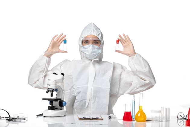 外套正面图年轻女医生穿着白色防护服带口罩因柯维德手持烧瓶背景白色大流行飞溅病毒健康柯维德-病毒医学实验室外套