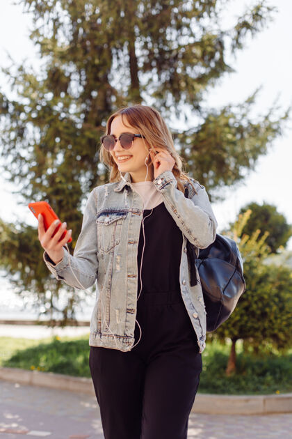 手机一个积极开朗的少女花时间在公园和使用手机的照片女人短信应用程序
