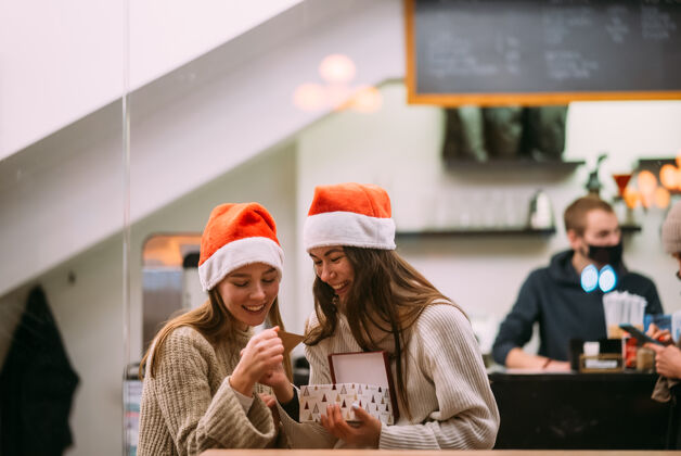 圣诞帽那个女孩在咖啡馆给她的女朋友送礼物女人灯圣诞节