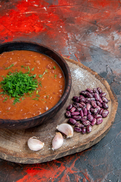 镜头番茄汤豆蒜的垂直视图在木砧板上混合颜色背景西红柿汤碗胡椒