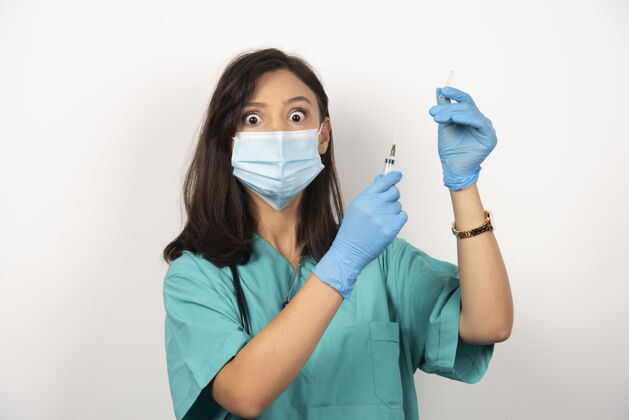 手套戴着医用面罩和手套的年轻医生在白色背景上准备注射器高质量照片保健医生疫苗