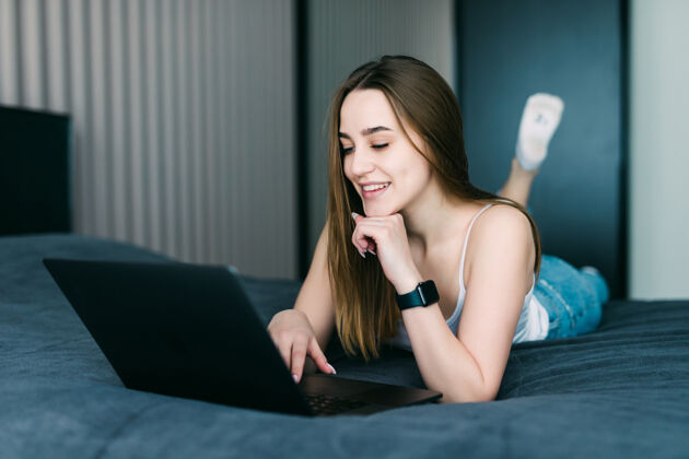 公寓漂亮女人在家里的床上用她的笔记本电脑靠垫和平女性