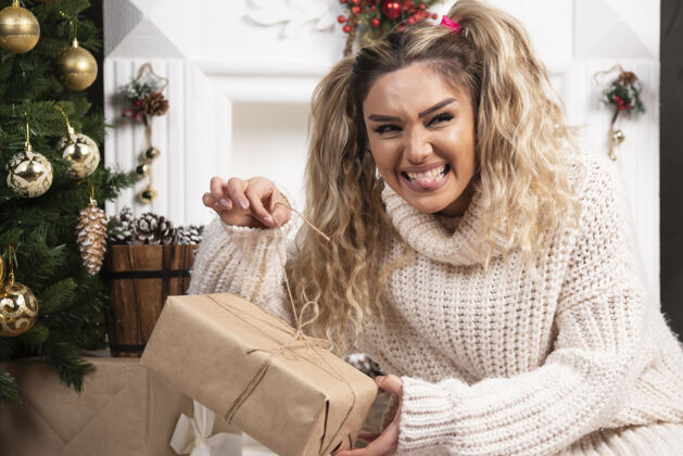 礼物一个穿着白色毛衣的年轻女子展示着两盒圣诞礼物女人礼物圣诞节