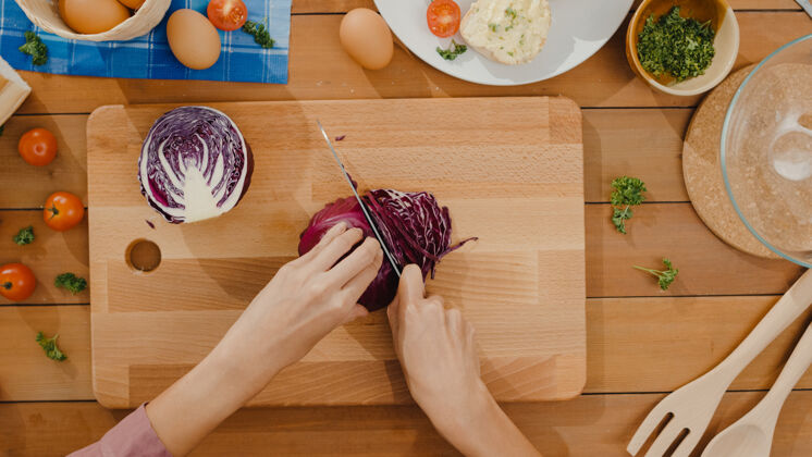 蔬菜年轻的亚洲女厨师手拿刀在木板上切红白菜刀餐桌鸡蛋