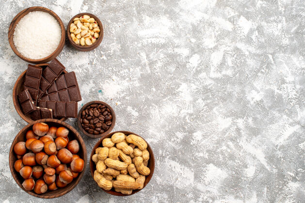 食物白色表面有榛子和花生的巧克力棒俯视图巧克力棒早餐榛子