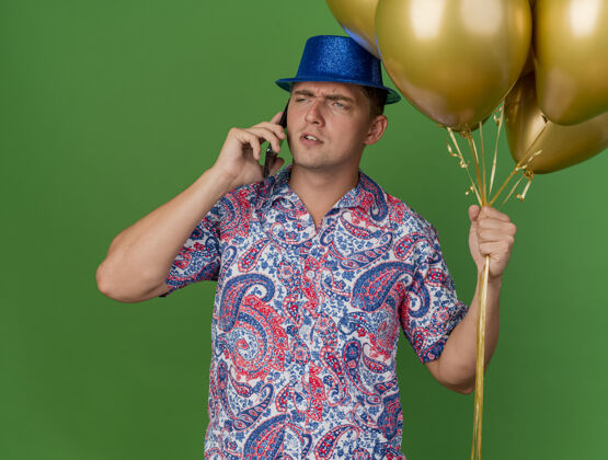 蓝色一个戴着蓝帽子 拿着气球 讲电话的体贴的年轻人年轻说话小伙子