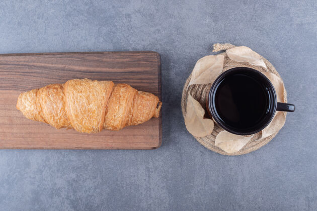 木头咖啡和羊角面包的顶视图灰色背景上的经典法式早餐小吃传统面包卷