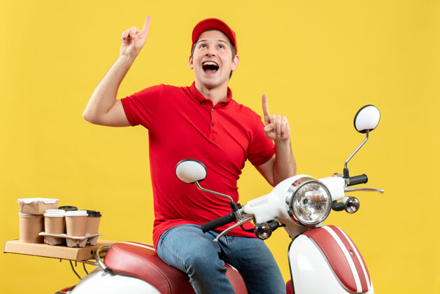 男人一个身穿红色上衣 戴着帽子 微笑着传递订单的年轻人出现在黄色背景上的正视图摩托车健身人
