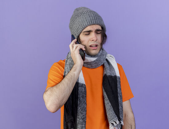 电话戴着围巾的冬天帽子的虚弱的生病的年轻人在电话里说孤立的紫色疾病帽子说话