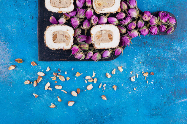 花卉蓝色桌子上放着一块木板 上面放着甜食和干玫瑰健康干有机
