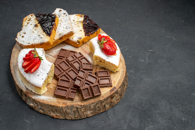 食物前视图美味的蛋糕片与水果和巧克力酒吧在黑暗的背景甜点面包前面