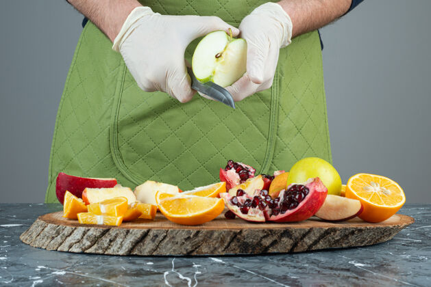 手套男手切青苹果放在桌上的木板上手准备刀
