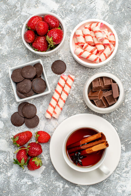 膳食顶视图碗与草莓巧克力糖果和肉桂八角种子茶马赛克灰白色地面浆果糖果种子