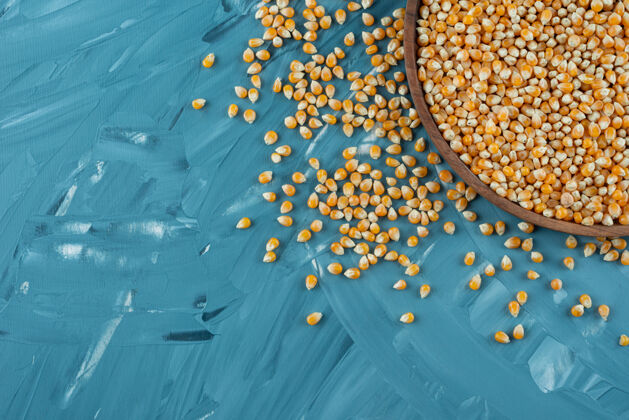 玉米蓝色表面上放着生玉米粒的木盘有机食品滋养农作物