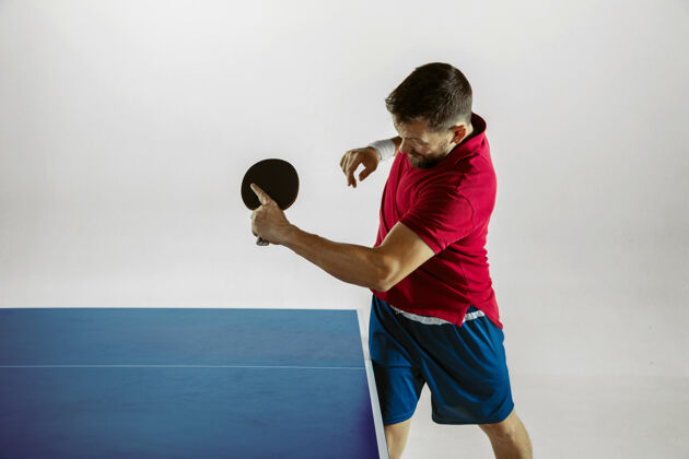 室内在白色工作室墙上打乒乓球的年轻人球拍休闲活动