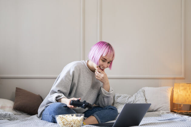 技术粉红色头发的女人在玩笔记本电脑上的操纵杆女人玩家数字