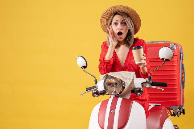 轻便摩托车一位身着红色连衣裙的年轻女士手持咖啡杯 坐在轻便摩托车旁 眼前一亮脸前面人