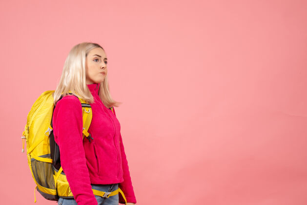 漂亮正面图：站在粉红色墙上的一个带着背包的前卫旅行者女人头发站人