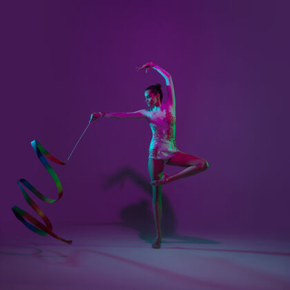 运动年轻的女运动员 艺术体操艺术家 舞蹈 在紫色的霓虹灯背景下孤立训练美丽的女孩用设备练习优雅的表演舞蹈比赛人