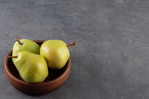 素食者把熟透的青梨放在木碗里放在石头表面梨一餐闪亮