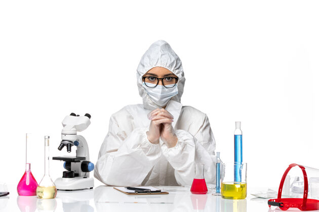 套装前视图穿着特殊防护服的女化学家坐在白色化学背景上解决病毒大流行健康化学病毒