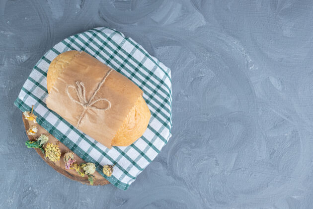 美味把面包包在大理石桌上用干花装饰的木板上面包房纸面包