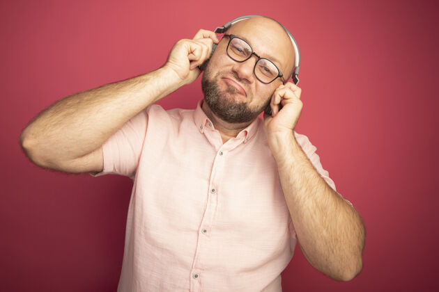 中年印象深刻的中年秃头男子穿着粉色t恤 戴着眼镜 戴着耳机印象人抱着