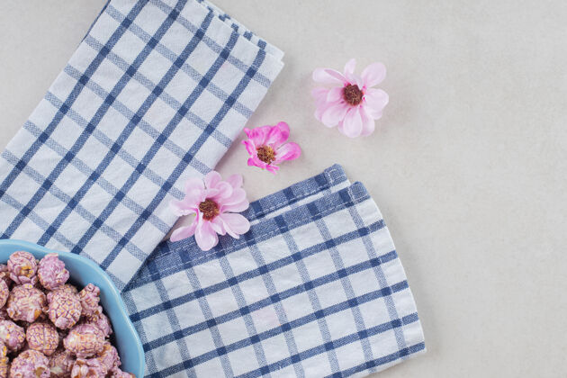 鲜花蓝色的爆米花糖果盘放在整齐折叠的毛巾上 旁边是大理石桌上的一排鲜花拼盘零食香