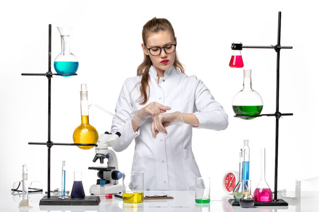 手腕前视图穿着医疗服的女化学家在浅白色背景上看着自己的手腕化学大流行的冠状病毒正面医学白色