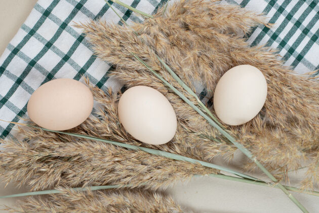 未料理的桌布上放三个新鲜的鸡蛋食物生的鸡肉