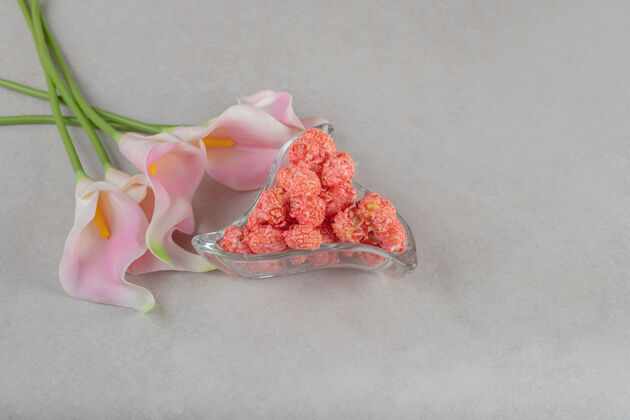 芳香鲜花堆在大理石桌上的爆米花糖果开胃盘旁边爆米花垃圾食品花